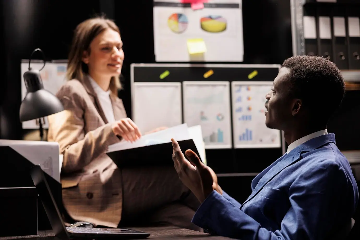 Vielfältige Mitarbeitende des Archivs analysieren eine bürokratische Akte und leisten Überstunden an einem Buchhaltungsbericht im Archivraum. Geschäftsleute prüfen administrative Dokumente im Unternehmensarchiv.